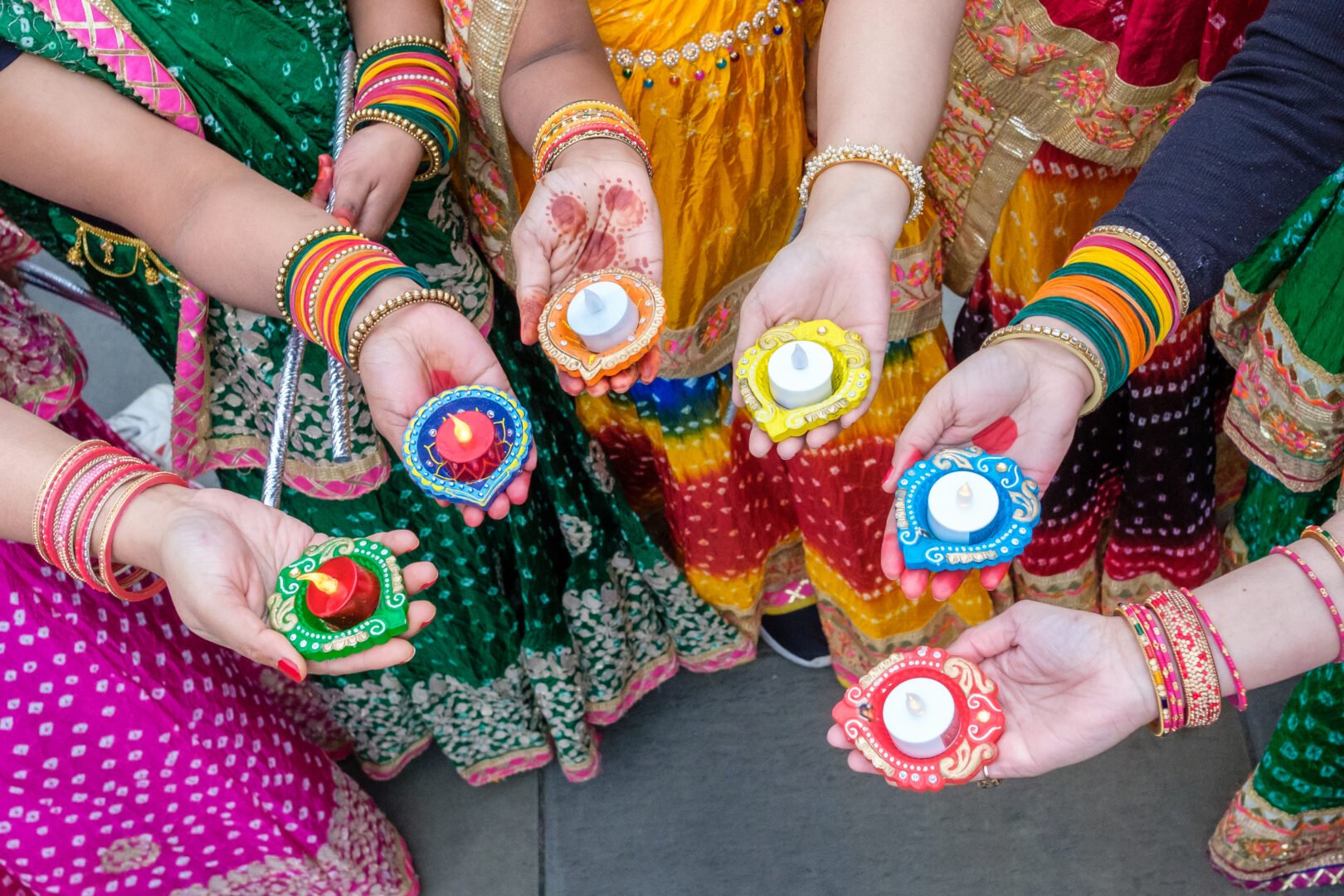 Close-up of hands holding tealights in holders.