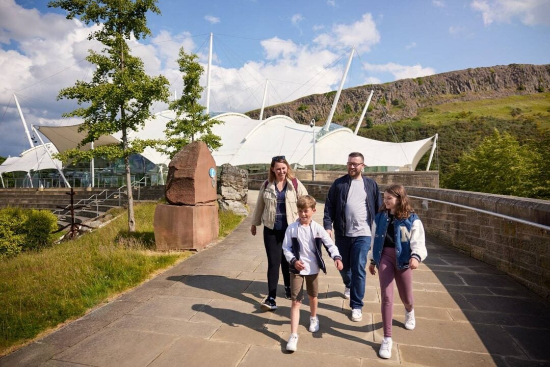 Happy Family group leaving Dynamic Earth with Arthur's Seat in the background.